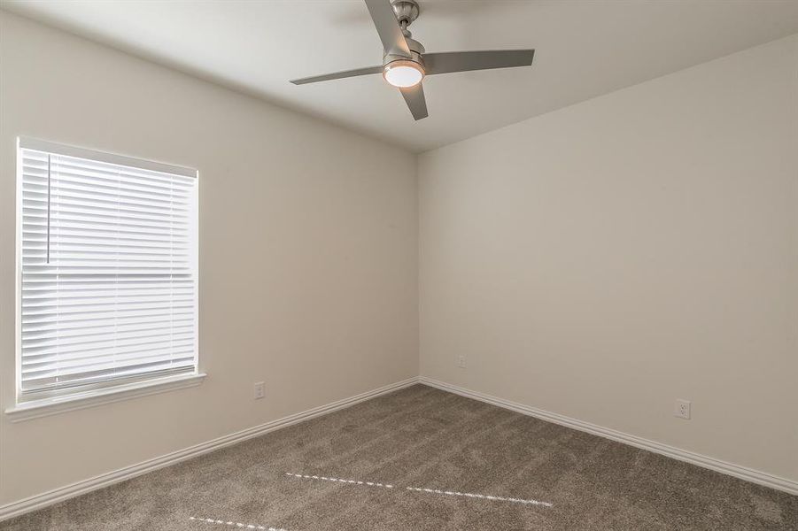 Spare room featuring ceiling fan and dark carpet