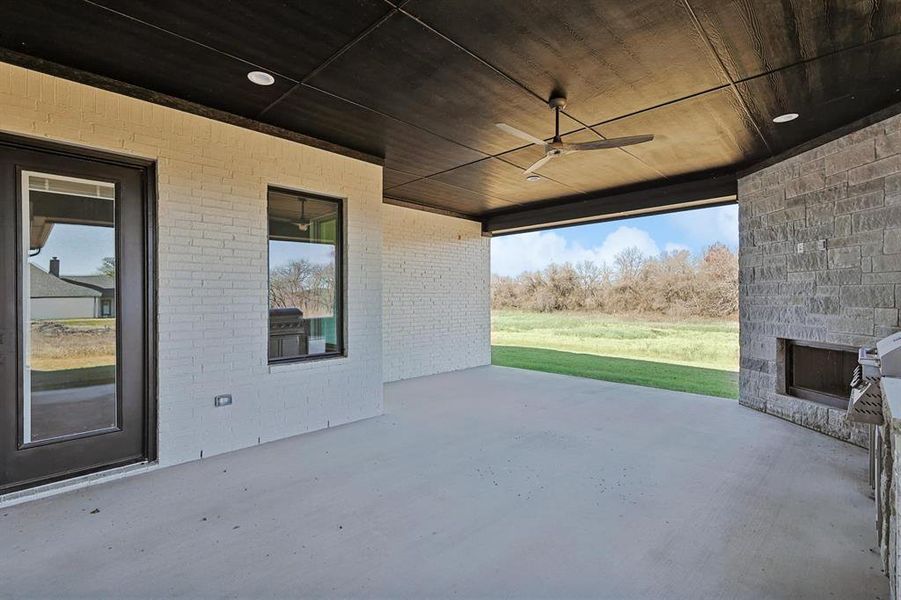 View of patio featuring an outdoor stone fireplace, ceiling fan, and a grill View of patio featuring an outdoor stone fireplace, ceiling fan, and a grill