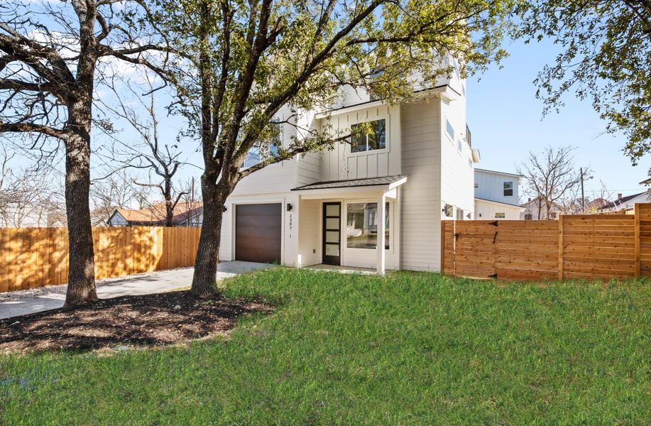 View of front of property with an attached garage, fence, concrete driveway, a front lawn, and board and batten siding