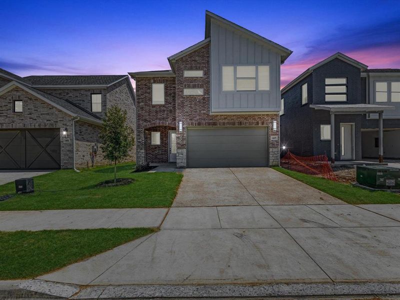View of front of home with board and batten siding, driveway, a yard, and an attached garage