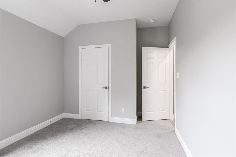 Unfurnished bedroom featuring lofted ceiling and light carpet