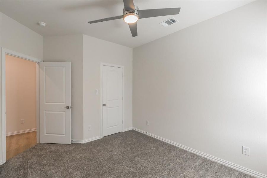 Unfurnished bedroom featuring dark colored carpet and ceiling fan