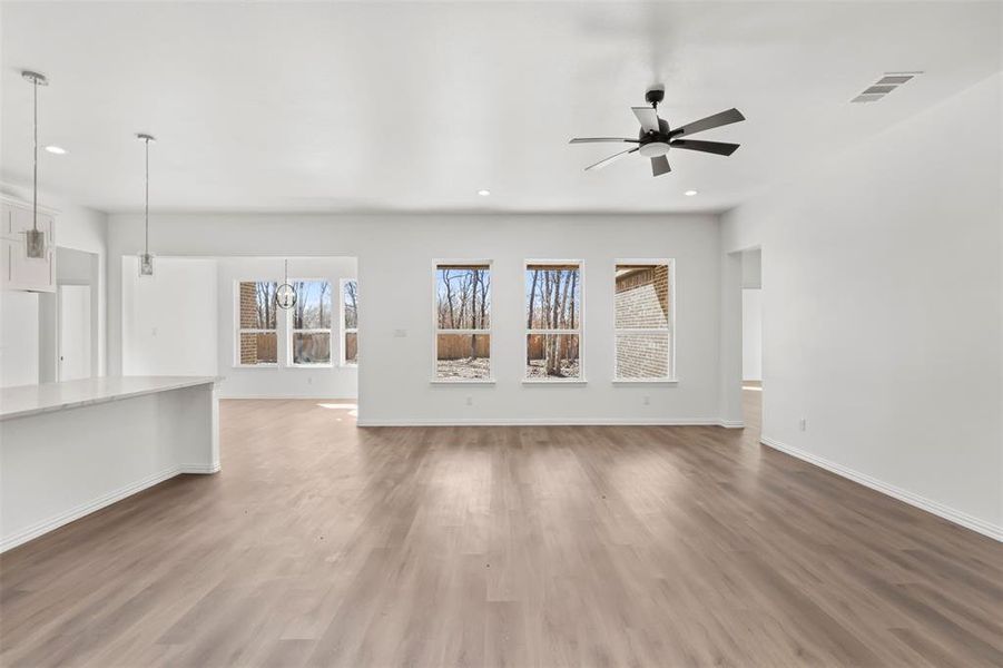 Unfurnished living room with hardwood / wood-style floors and ceiling fan with notable chandelier