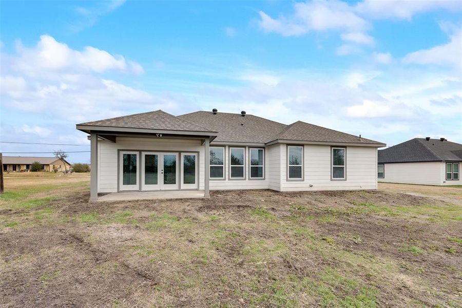 Back of property featuring a patio, a yard, and french doors