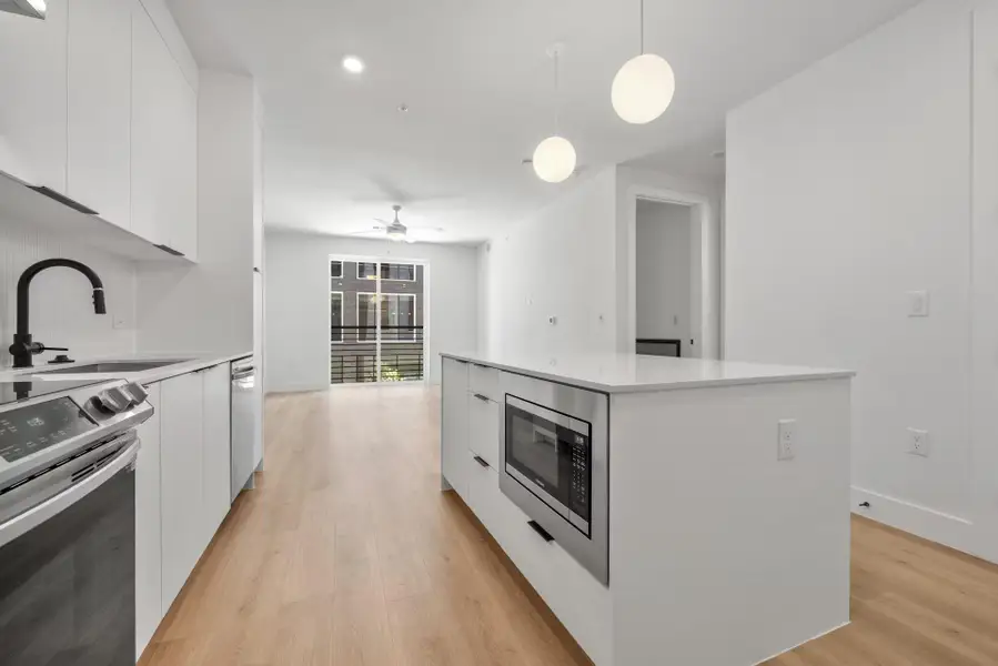 Kitchen with modern cabinets, appliances with stainless steel finishes, white cabinets, a kitchen island, and recessed lighting