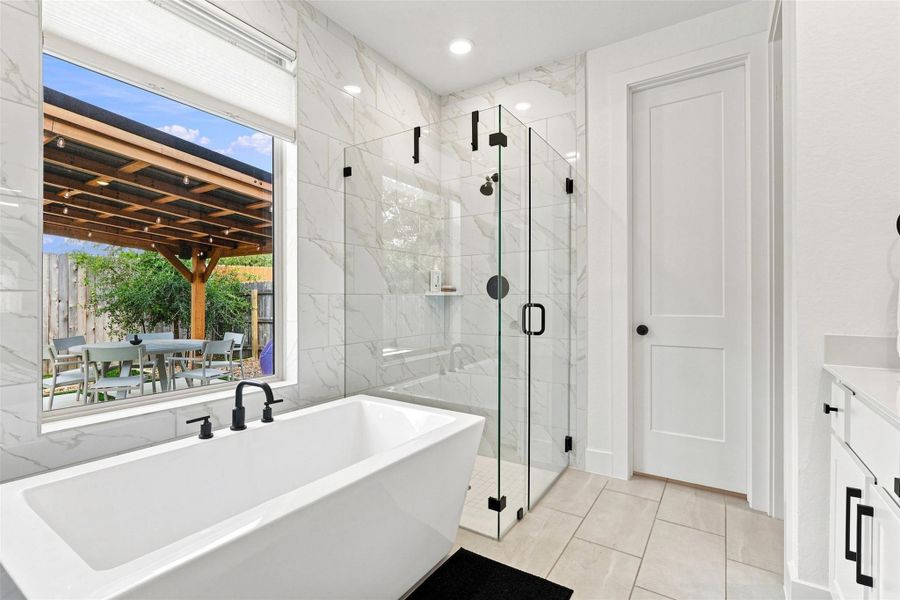 Marble-patterned tile wall accents a modern bathroom complete with a freestanding soaking tub.