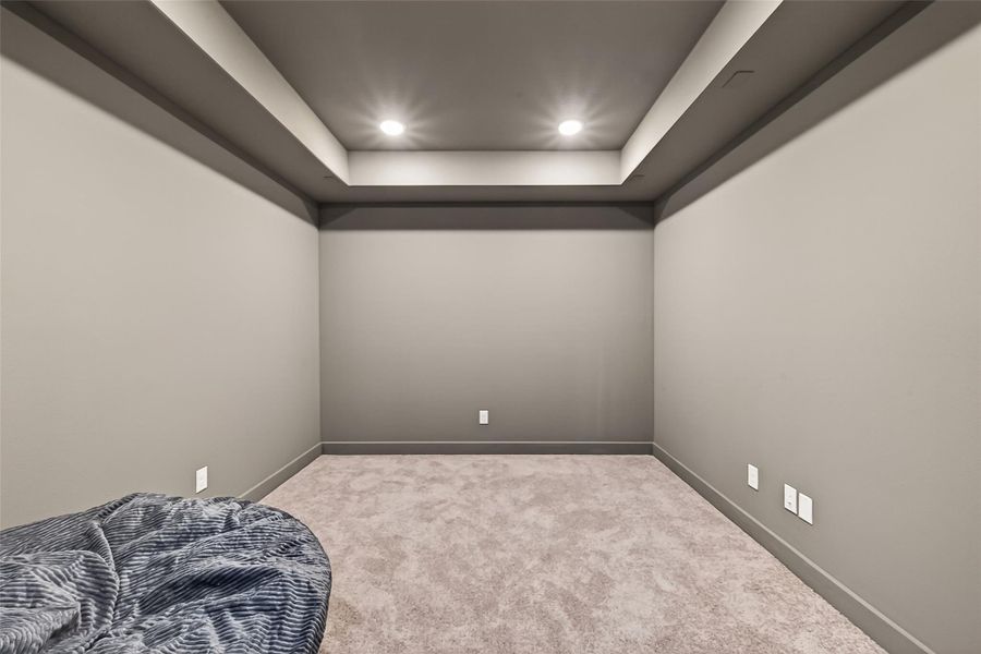 This media room is carpeted space with soft, neutral-toned walls and recessed lighting, perfect for a media or entertainment room.