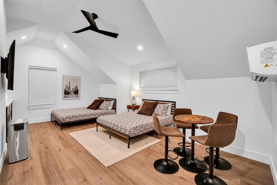 Bedroom with light wood finished floors, recessed lighting, ceiling fan, and lofted ceiling Bedroom with light wood finished floors, recessed lighting, ceiling fan, and lofted ceiling