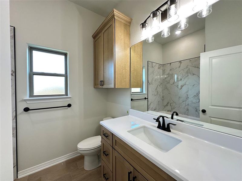 Full bath with vanity, plenty of natural light, and a marble finish shower