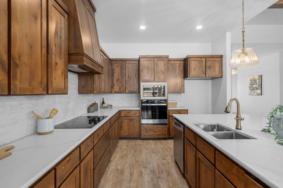 Kitchen with light stone counters, stainless steel appliances, decorative backsplash, light wood-style floors, and wood finish cabinetry