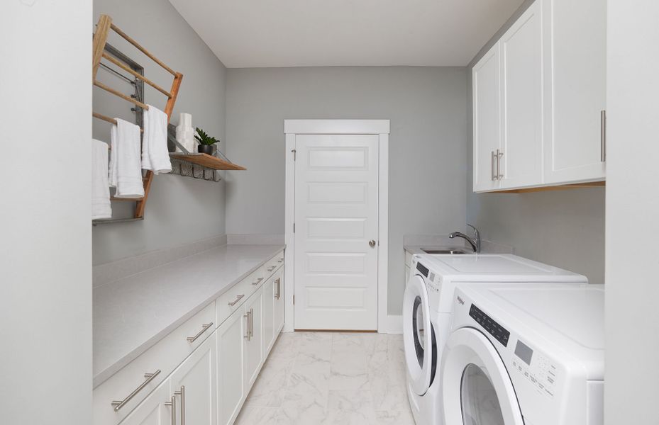 This spacious Laundry Room features a utility sink and cabinets