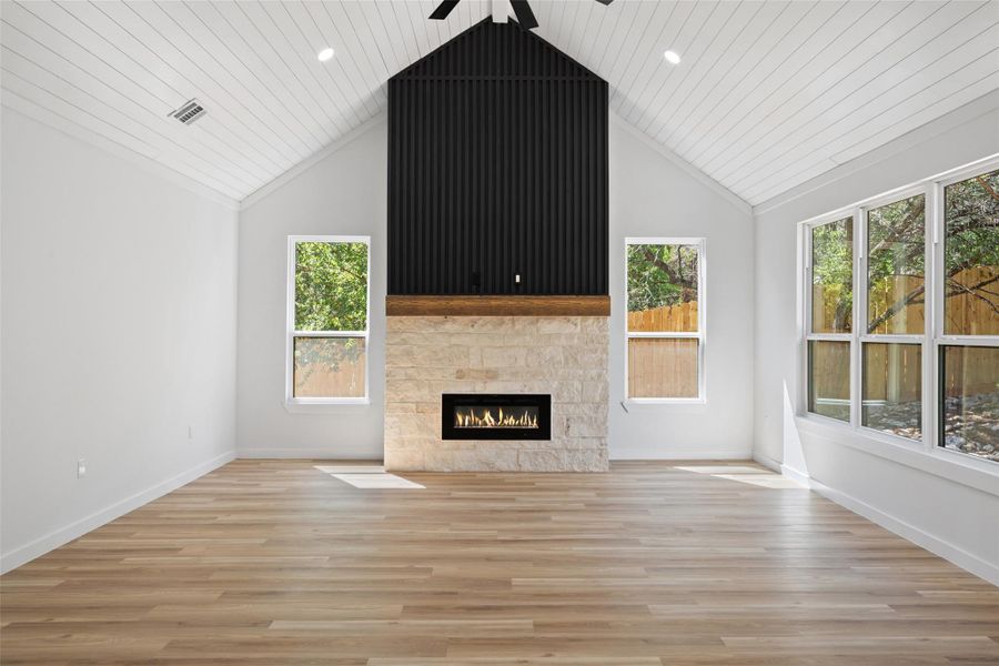 Unfurnished living room with light wood-style flooring, a fireplace, a ceiling fan, wood ceiling, and high vaulted ceiling Unfurnished living room with light wood-style flooring, a fireplace, a ceiling fan, wood ceiling, and high vaulted ceiling