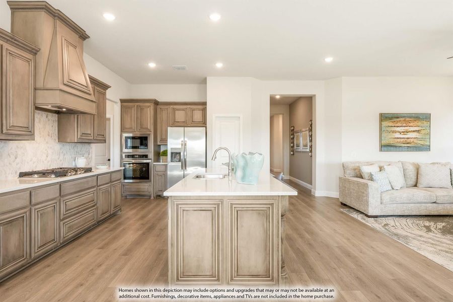 Open kitchen with tan wood cabinets, center island, stainless appliances, and wood floors, open to living room Open kitchen with tan wood cabinets, center island, stainless appliances, and wood floors, open to living room