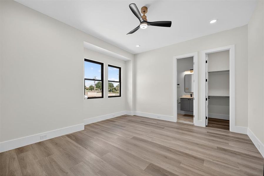 Unfurnished bedroom featuring a walk in closet, light wood-style flooring, a ceiling fan, recessed lighting, and connected bathroom