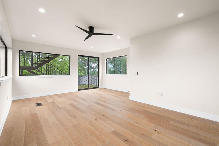 Spacious interior with light wood-finish flooring, recessed lighting, and a modern black ceiling fan