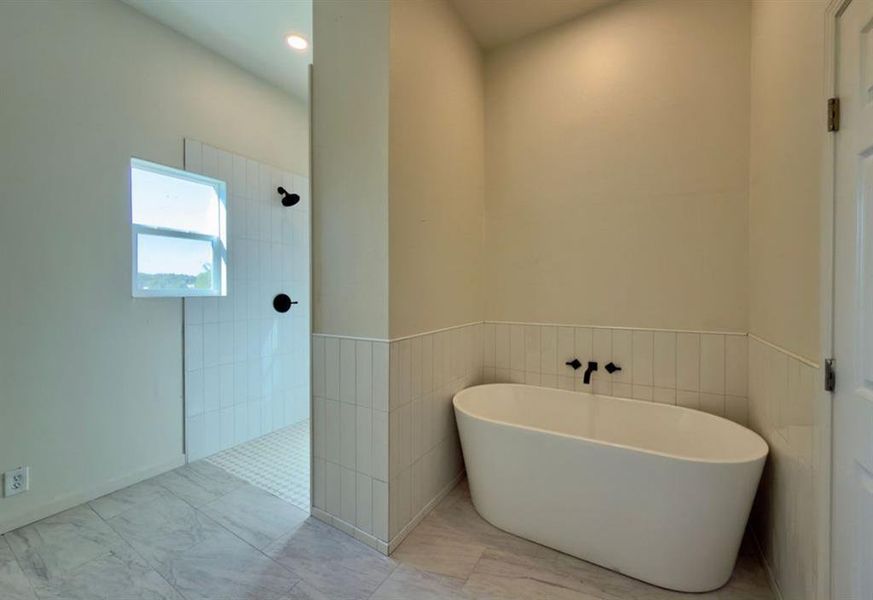 Bathroom with a freestanding bath, walk in shower, tile walls, and a wainscoted wall Bathroom with a freestanding bath, walk in shower, tile walls, and a wainscoted wall