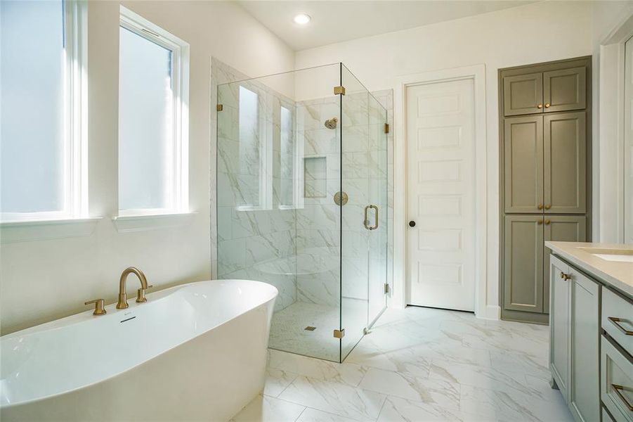 Full bath with a freestanding bath, light marble finish floors, vanity, and a marble finish shower
