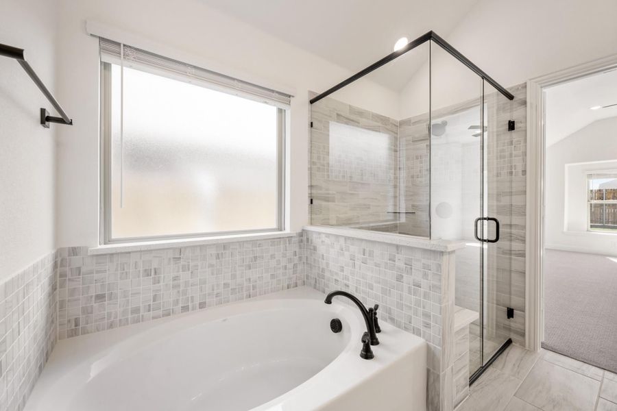 Master bathroom with soaking tub, glass-enclosed shower, gray tile walls, and black fixtures Master bathroom with soaking tub, glass-enclosed shower, gray tile walls, and black fixtures