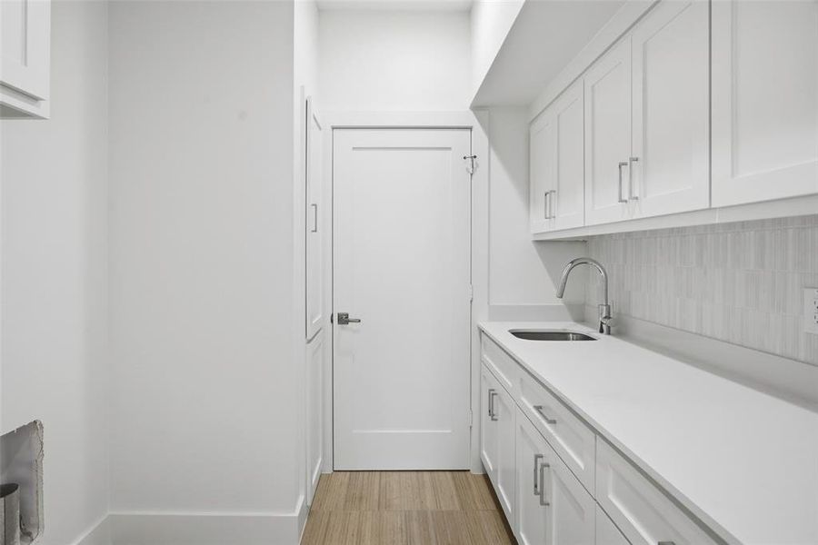 Designated room with room for full size washer and dryer, sink and cabinetry