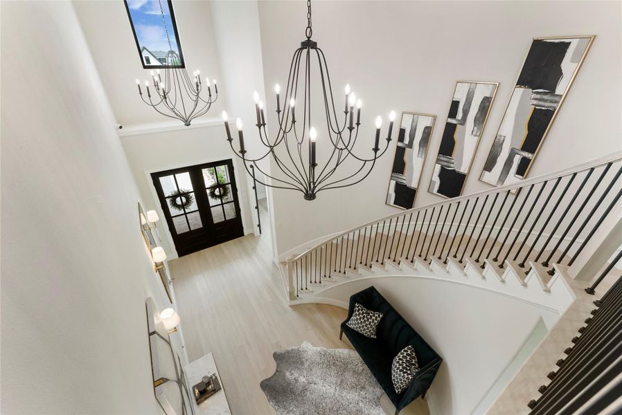 Epic stair view highlights the home’s architectural presence with curved railing, tall windows, and upgraded lighting. The layout creates a beautiful transition between the main level and private upstairs spaces.
