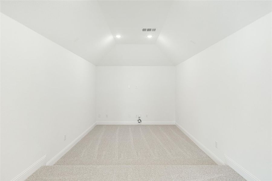 Empty room with vaulted ceiling, recessed lighting, and neutral carpet flooring Empty room with vaulted ceiling, recessed lighting, and neutral carpet flooring