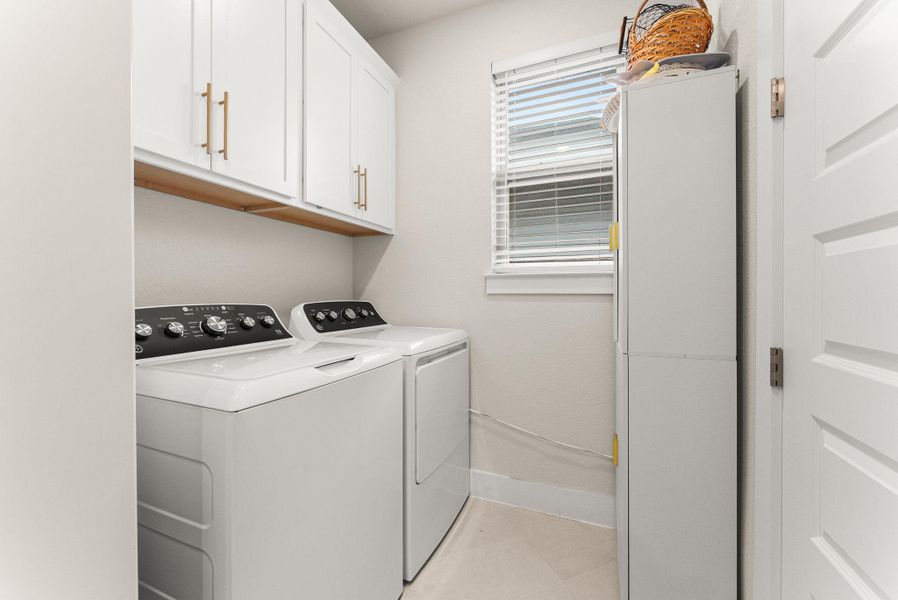 The laundry room has built-in cabinets, a window with two-inch blinds, and direct access to the master closet.