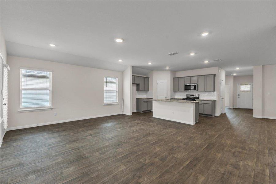 The property features an open-concept living area with wood-look flooring, recessed lighting, and a kitchen with an island, grey cabinetry, and stainless steel appliances