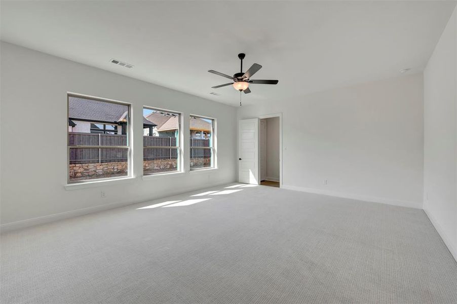 Empty room with light colored carpet and a ceiling fan