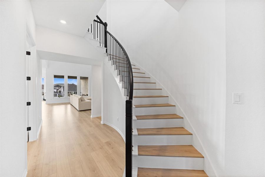 Staircase with wood finished floors, a high ceiling, and recessed lighting