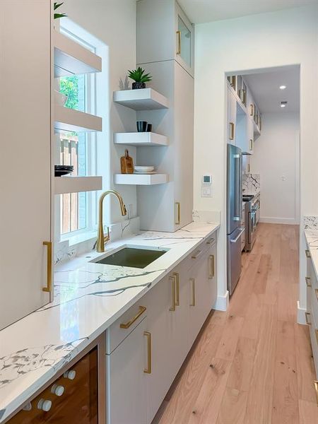 Kitchen with open shelves, plenty of natural light, light wood-style flooring, and modern cabinets Kitchen with open shelves, plenty of natural light, light wood-style flooring, and modern cabinets