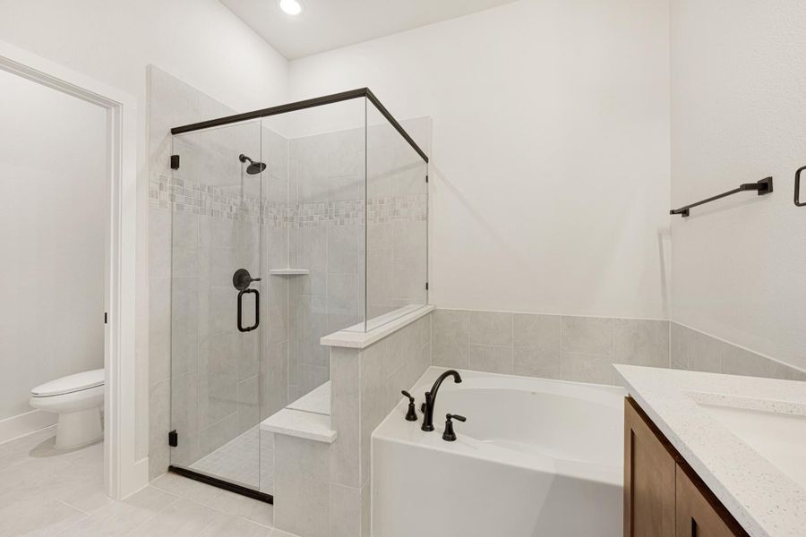 Bathroom with glass walk-in shower, soaking tub, and wood vanity with white countertop
