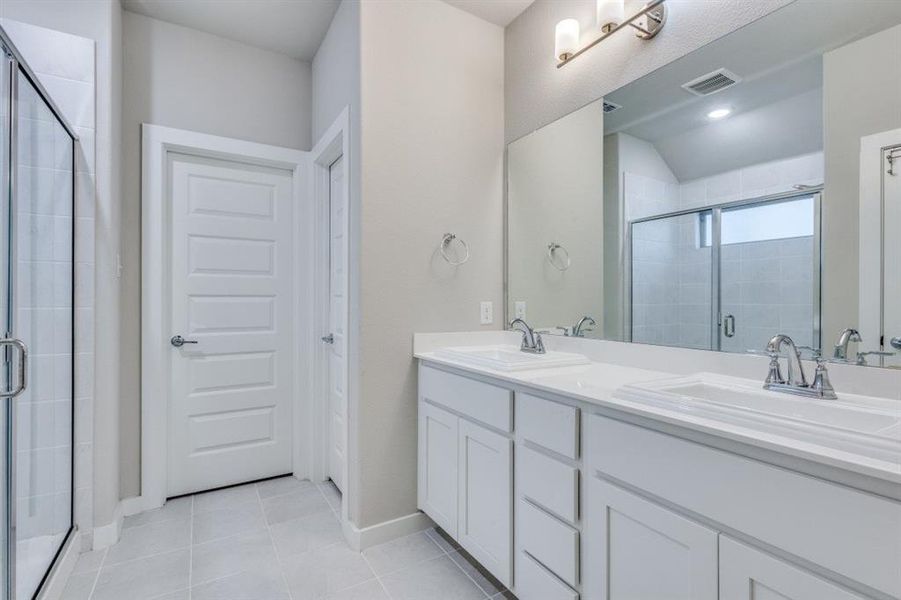 Bathroom featuring double vanity, a stall shower, and light tile patterned floors Bathroom featuring double vanity, a stall shower, and light tile patterned floors