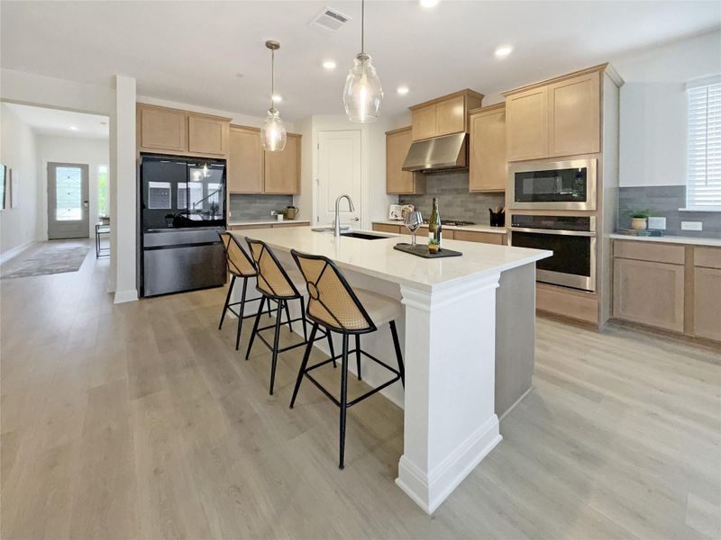 Kitchen featuring healthy amount of natural light, a breakfast bar area, light wood finish cabinets, and stainless steel appliances