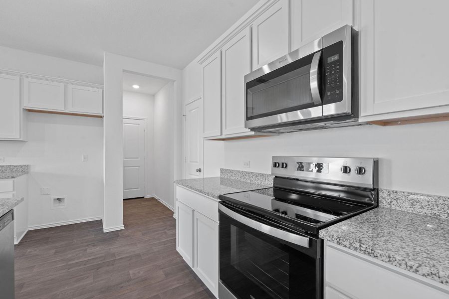 Kitchen featuring appliances with stainless steel finishes, light stone countertops, white cabinets, dark wood finished floors, and recessed lighting Kitchen featuring appliances with stainless steel finishes, light stone countertops, white cabinets, dark wood finished floors, and recessed lighting