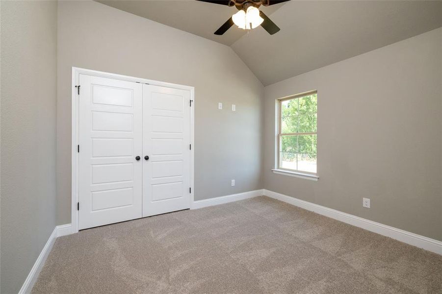 Unfurnished bedroom featuring a closet, carpet, lofted ceiling, and ceiling fan