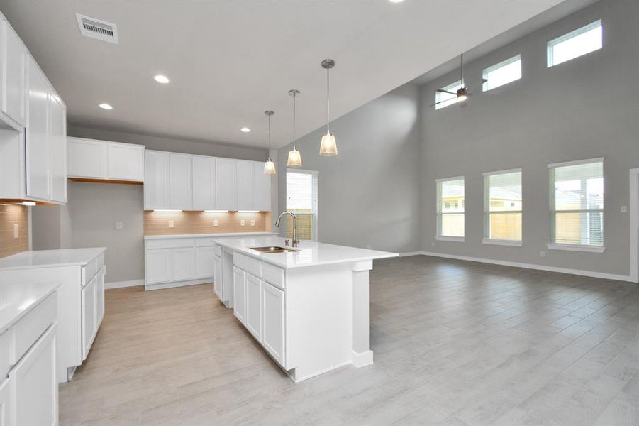 This generously spacious kitchen is a dream realized! With a massive granite island, high ceilings, soft close cabinets, granite countertops, stainless steel appliances (to be installed), a sleek tile backsplash, recessed and pendant lighting, it offers both style and practicality. All this opens up to the expansive family room, creating a perfect hub for gatherings. Sample photo of completed home with similar plan. As built color and selections may vary.