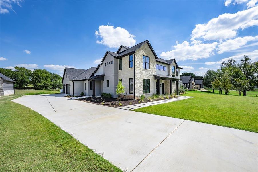View of front of house featuring stone siding, a front yard, driveway, a garage, and stucco siding