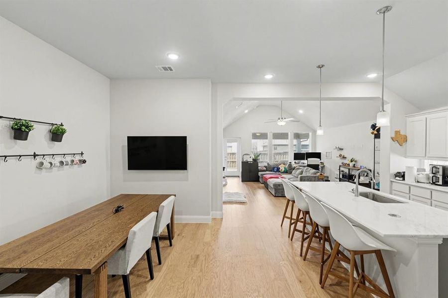 Open-concept living space featuring wood-finish flooring, recessed lighting, and a vaulted ceiling