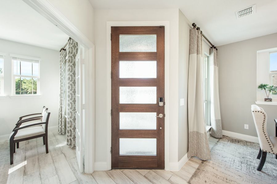 Home entryway with dark wood front door featuring five frosted glass panels and light hardwood floors