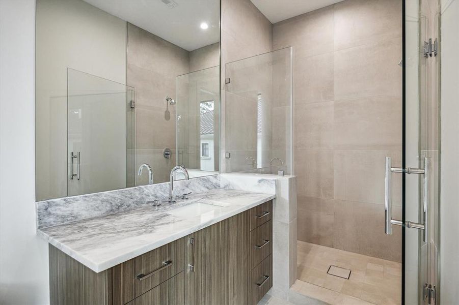 This guest bathroom No. 3 features a walk-in shower with a seamless glass door and a Grohe shower trim kit, ensuring a luxurious bathing experience. It includes a Kohler under-mount bathroom sink, a Duravit one-piece commode, and a Grohe widespread sink faucet in polished chrome, adding sophistication to the space. Designer-neutral wall paint and recessed LED lighting complete the modern and inviting ambiance of this bathroom.