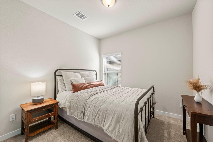A comforting bedroom space features soft carpet flooring and a sun-filled window. A comforting bedroom space features soft carpet flooring and a sun-filled window.