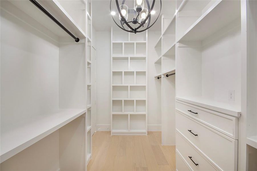Spacious closet with a chandelier and light wood-style flooring Spacious closet with a chandelier and light wood-style flooring