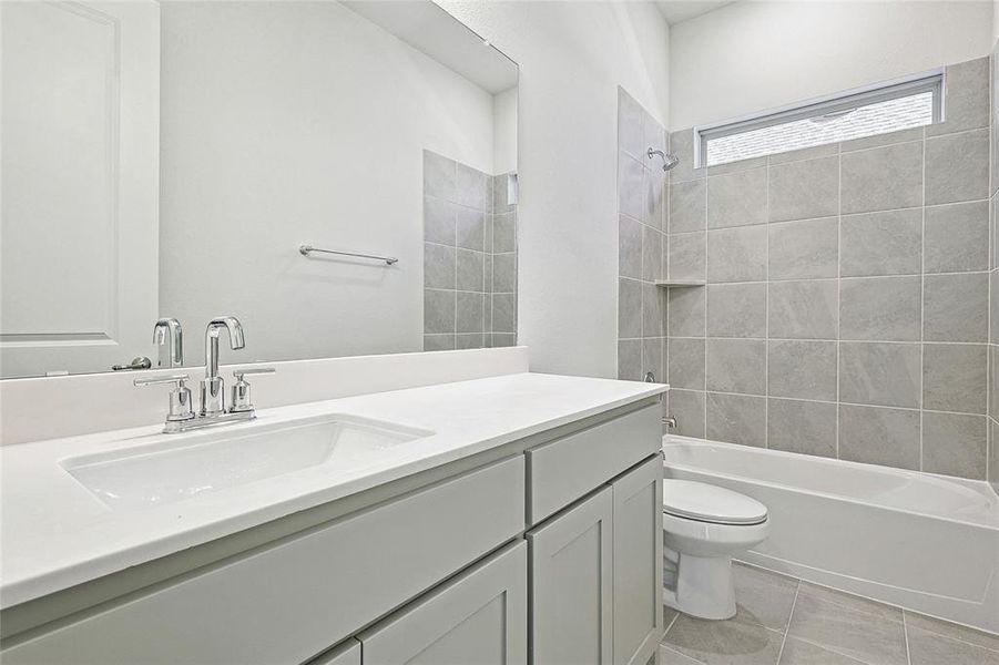 Full bathroom featuring tile patterned floors, tiled shower / bath, vanity, and toilet