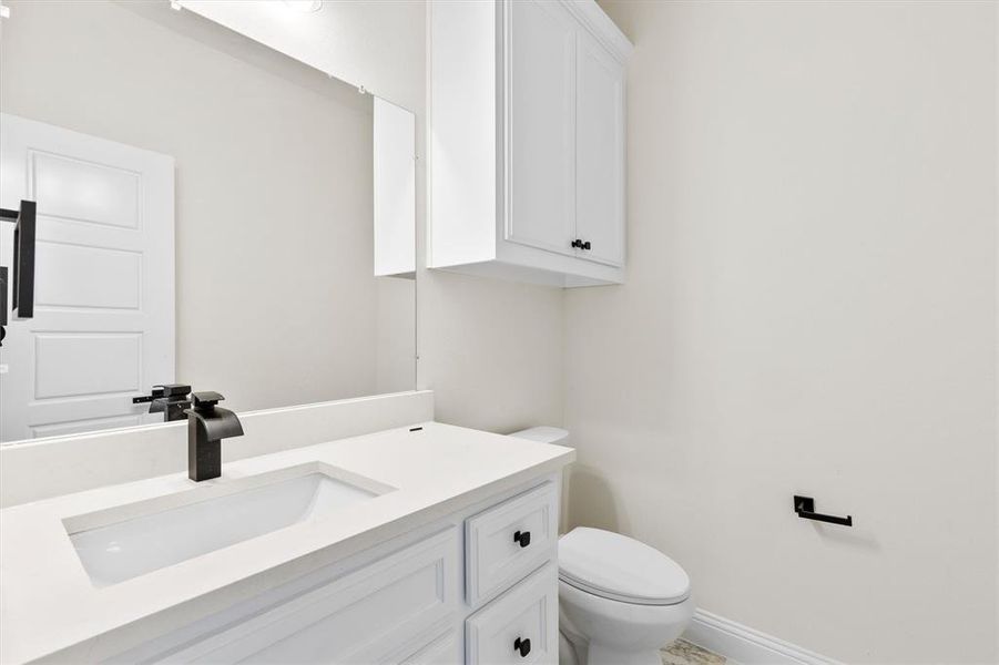 Half bath with toilet, baseboards, and vanity Half bath with toilet, baseboards, and vanity