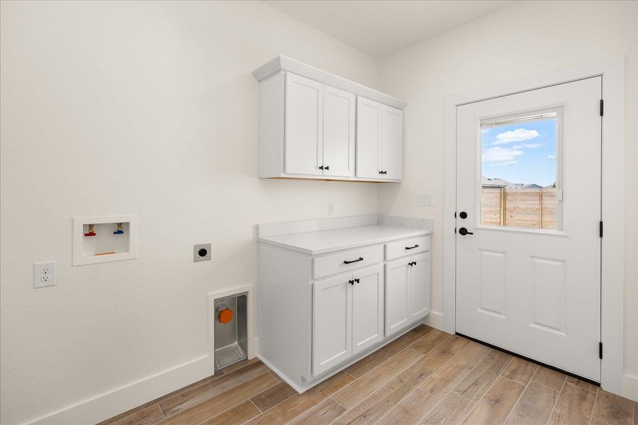 Functional utility space with built-in cabinetry and durable wood-look flooring.