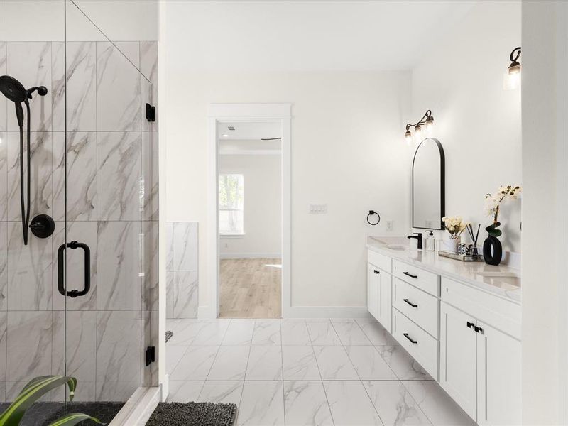 Full bathroom with double vanity, a marble finish shower, and light marble finish flooring