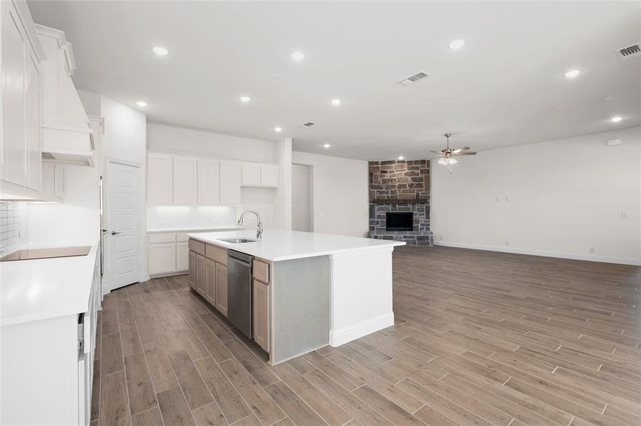 Kitchen with recessed lighting, an island with sink, a fireplace, a ceiling fan, and open floor plan Kitchen with recessed lighting, an island with sink, a fireplace, a ceiling fan, and open floor plan