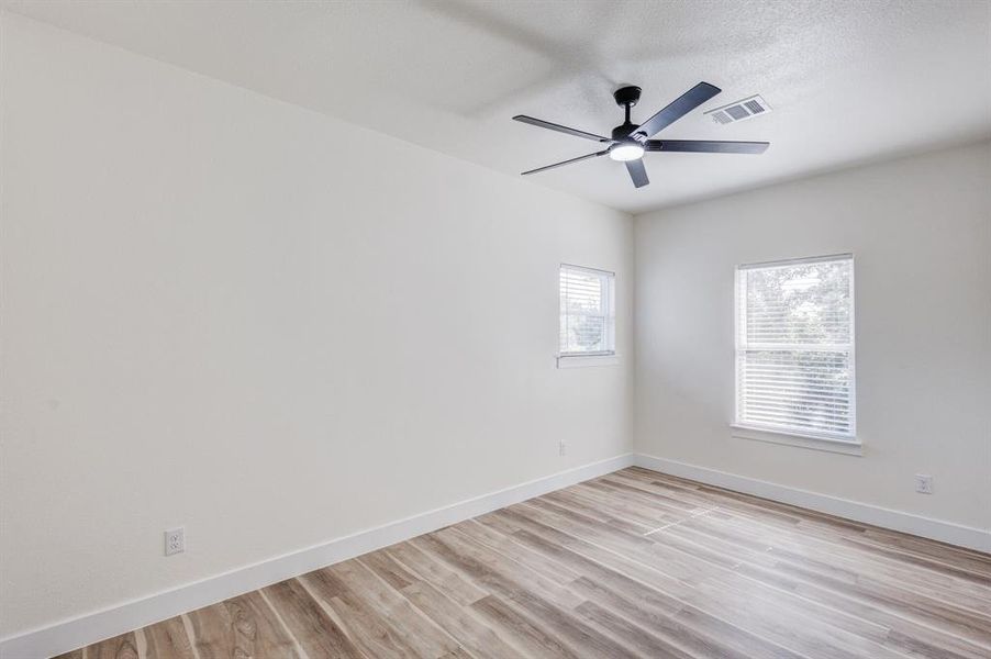 Spare room with a textured ceiling, ceiling fan, and light hardwood / wood-style flooring