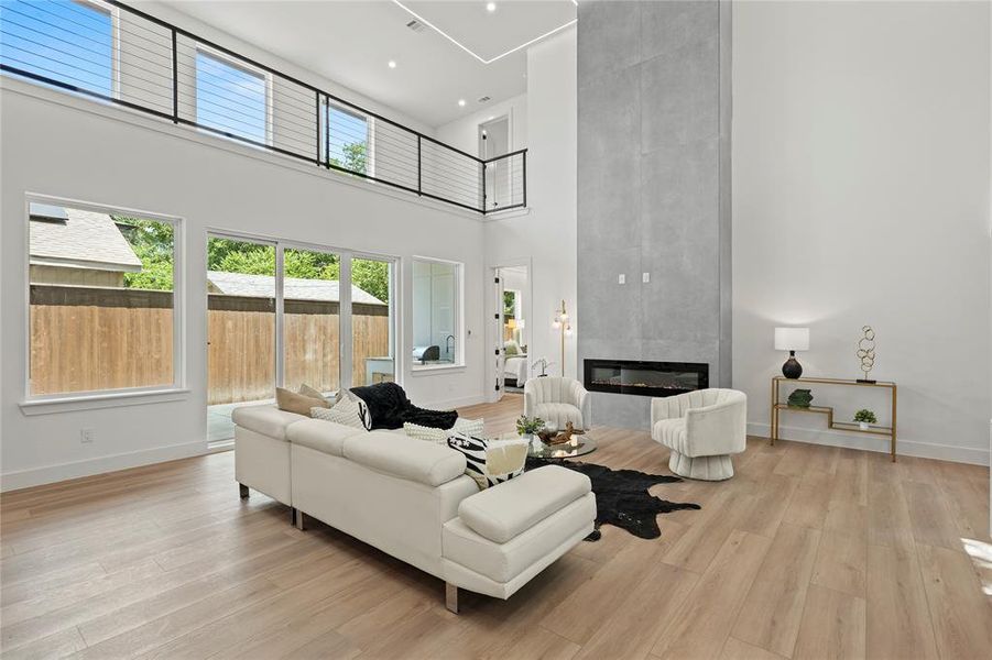 Living area with a towering ceiling, light wood finished floors, and a premium fireplace