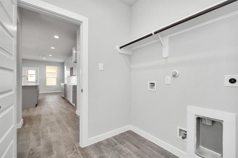 Located on first floor, a stylish laundry room where practicality meets a contemporary aesthetic. The dark finishes lend a sophisticated touch, creating a space that is both functional and visually appealing. Both electric and gas connections available. Sample photo of completed home with similar floor plan. As-built interior colors and selections may vary.